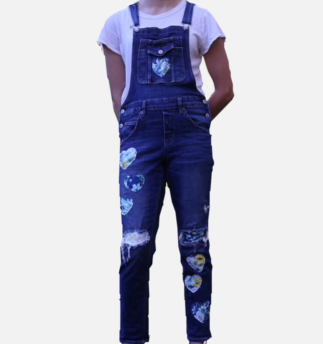 Person wearing blue denim overalls with heart patterns on a white background