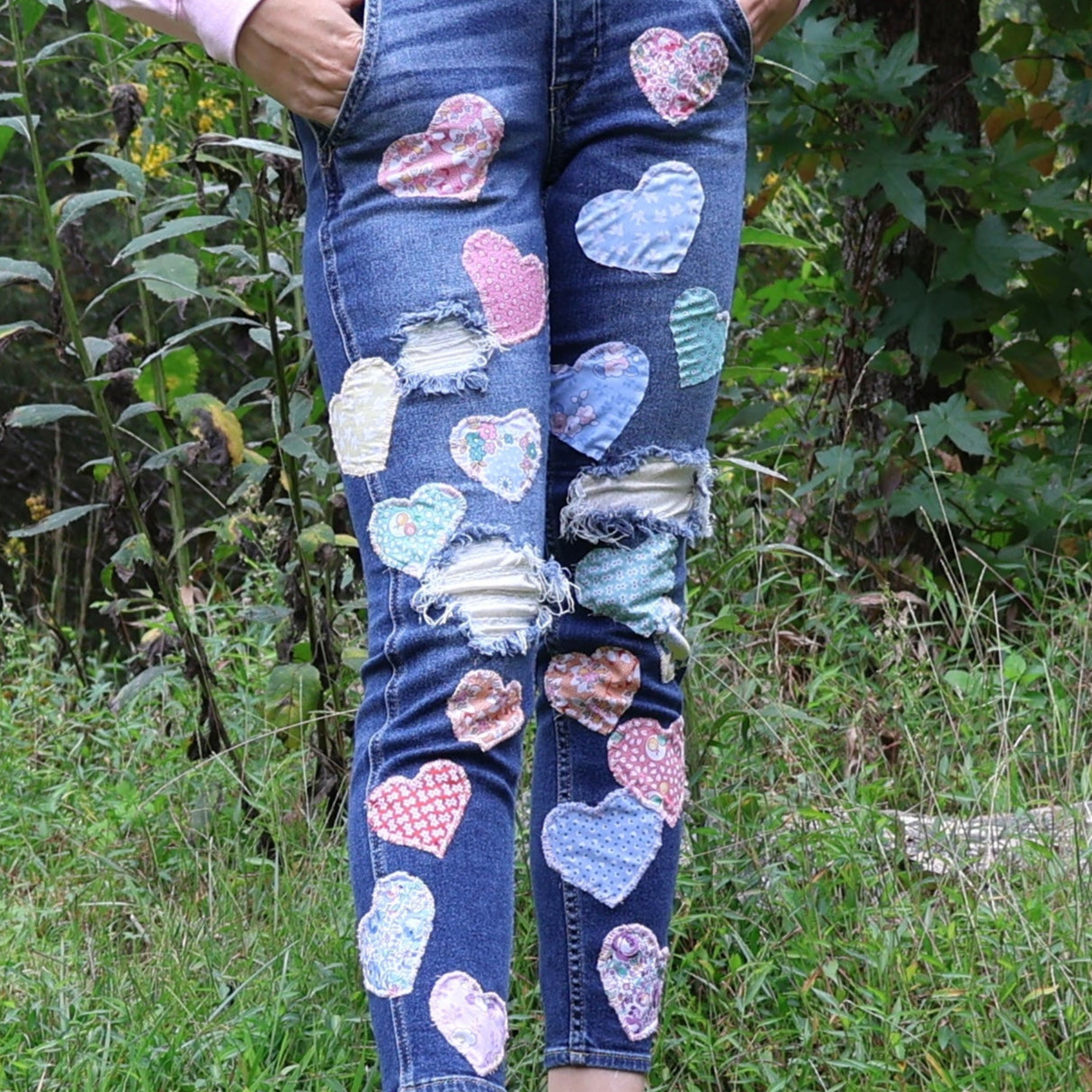 Person wearing blue denim overalls with heart patterns in a natural setting