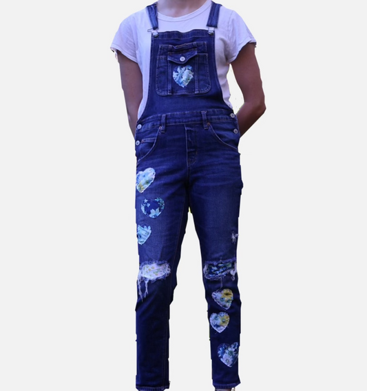 Person wearing blue denim overalls with heart patterns on a white background