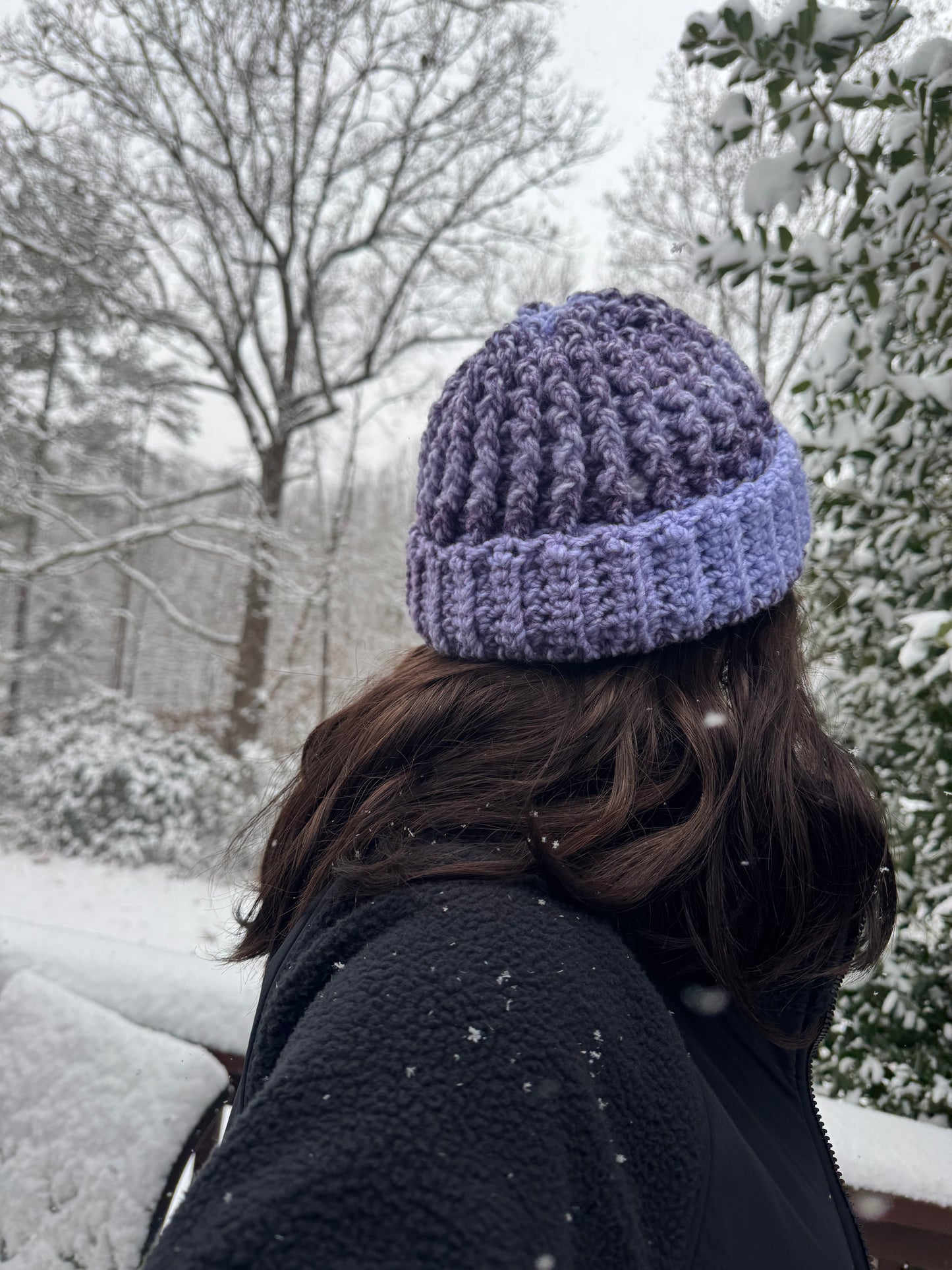 Person wearing a purple knit beanie in a snowy outdoor setting